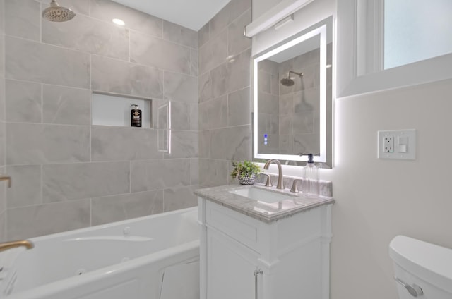 full bath featuring tiled shower / bath, vanity, and toilet