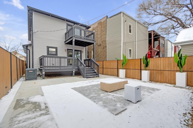 rear view of house with a balcony, a fenced backyard, and central AC
