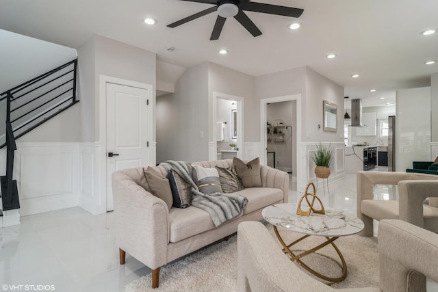 living area featuring recessed lighting, a decorative wall, a ceiling fan, and a wainscoted wall