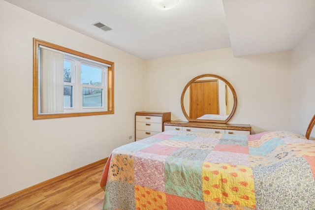 bedroom with baseboards, wood finished floors, and visible vents