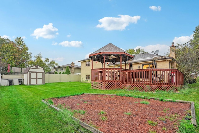 rear view of property featuring a chimney, a fenced backyard, a storage shed, a lawn, and a gazebo