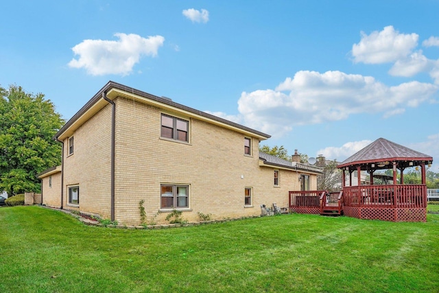 rear view of house featuring a gazebo, brick siding, a wooden deck, and a lawn