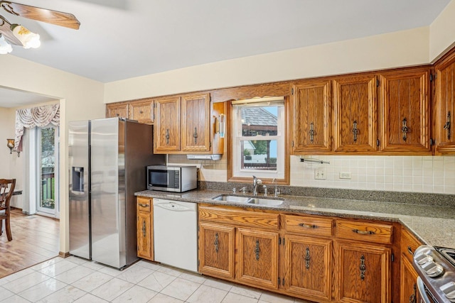 kitchen featuring stainless steel appliances, a sink, and brown cabinets