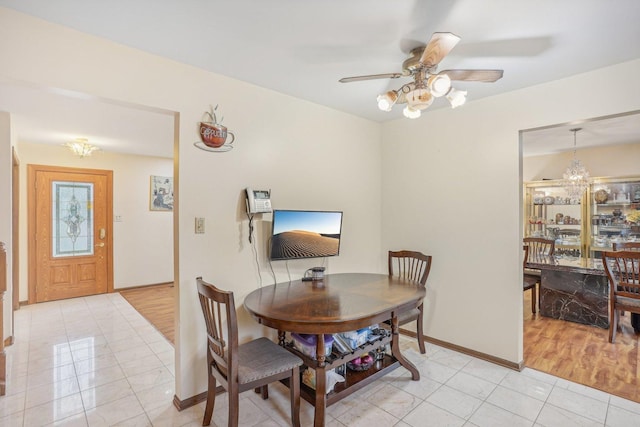 dining area with baseboards, light tile patterned flooring, and ceiling fan with notable chandelier