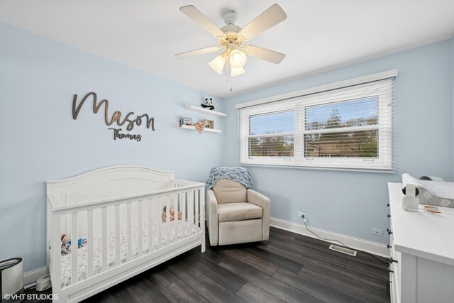 bedroom featuring visible vents, baseboards, ceiling fan, dark wood-style floors, and a crib