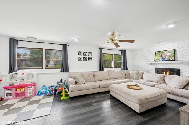 living room with ceiling fan, a brick fireplace, dark wood-style flooring, and visible vents