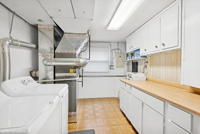 laundry area with electric panel, independent washer and dryer, and cabinet space