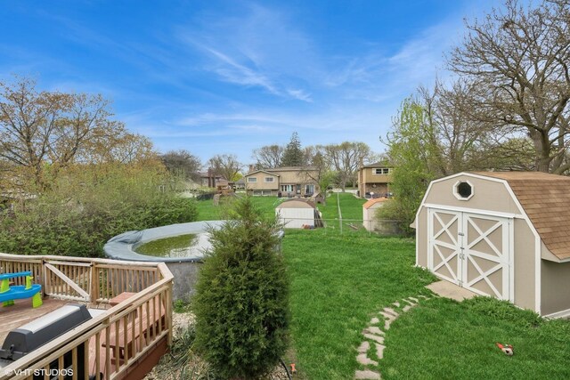 view of yard featuring a deck, a residential view, an outbuilding, fence, and a shed