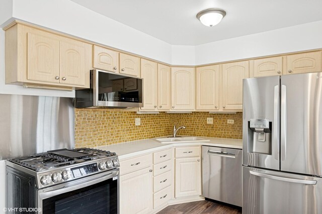 kitchen featuring light brown cabinets, dark wood-type flooring, light countertops, a sink, and appliances with stainless steel finishes