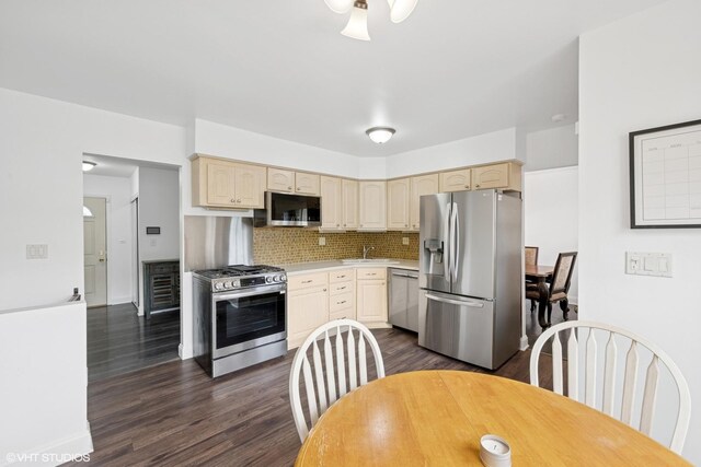 kitchen with decorative backsplash, dark wood-type flooring, light countertops, a sink, and appliances with stainless steel finishes