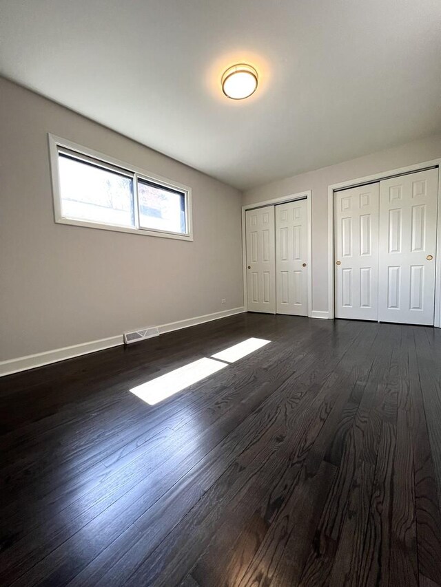 14301 Dorchester Ave, Dolton, IL 60419 - unfurnished bedroom with visible vents, baseboards, multiple closets, and dark wood finished floors