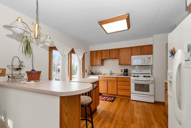 8509 Hemlock St, Orland Park, IL 60462 - kitchen with white appliances, a kitchen bar, light countertops, light wood finished floors, and backsplash