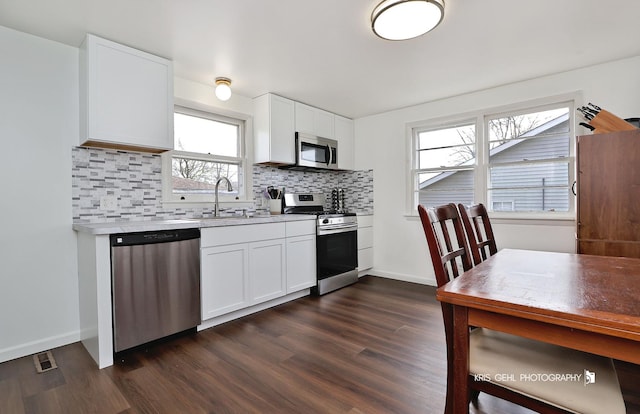 kitchen featuring appliances with stainless steel finishes, dark wood-style floors, decorative backsplash, and a sink