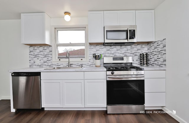 kitchen with white cabinets, stainless steel appliances, light countertops, and a sink