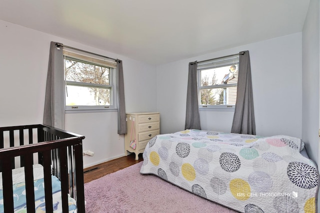 bedroom with wood finished floors and multiple windows