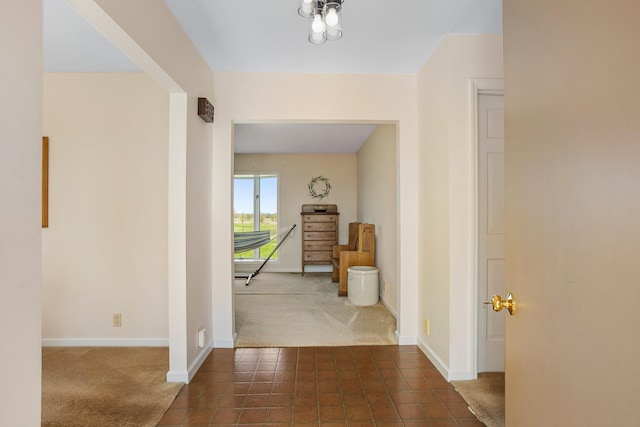 corridor with dark tile patterned flooring, baseboards, and dark colored carpet