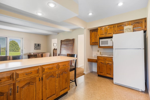 kitchen with light countertops, brown cabinets, white appliances, and light floors