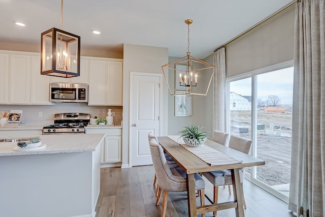 dining area with a chandelier, recessed lighting, and light wood-style floors