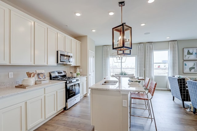 kitchen featuring a sink, appliances with stainless steel finishes, light wood-style floors, and white cabinetry