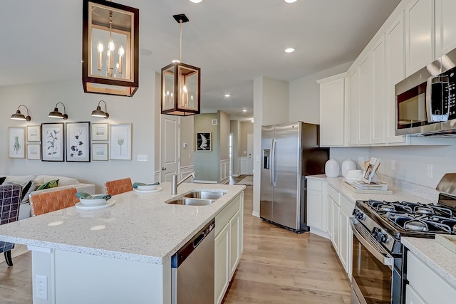 kitchen featuring appliances with stainless steel finishes, light wood finished floors, a sink, and white cabinetry