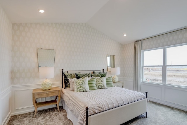 carpeted bedroom featuring a decorative wall, wainscoting, wallpapered walls, and lofted ceiling