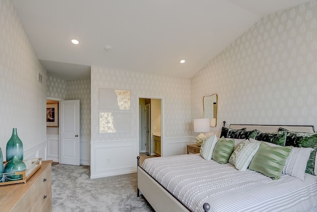 bedroom with wallpapered walls, a wainscoted wall, visible vents, lofted ceiling, and light colored carpet