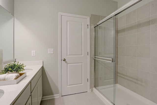 full bath with tile patterned flooring, baseboards, double vanity, and a stall shower