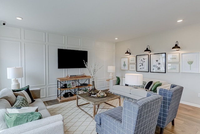 living room featuring a decorative wall, light wood finished floors, and recessed lighting