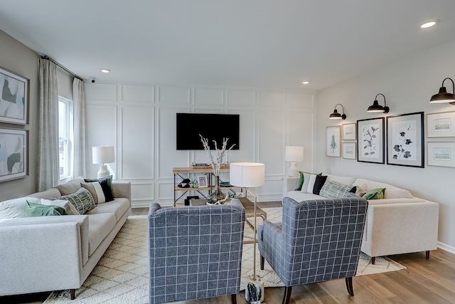 living area with a decorative wall, wood finished floors, and recessed lighting