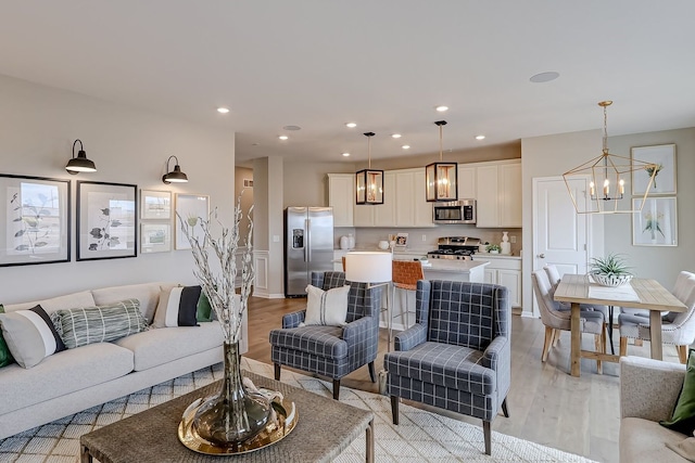 living area featuring light wood-type flooring, a notable chandelier, and recessed lighting