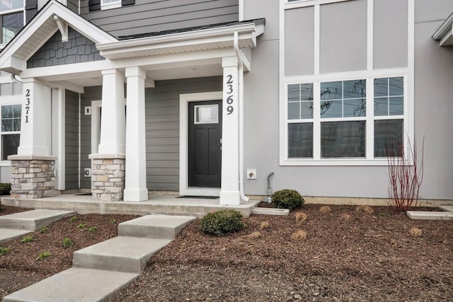 view of exterior entry with a porch and stone siding