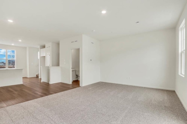 unfurnished living room featuring recessed lighting, baseboards, and dark carpet