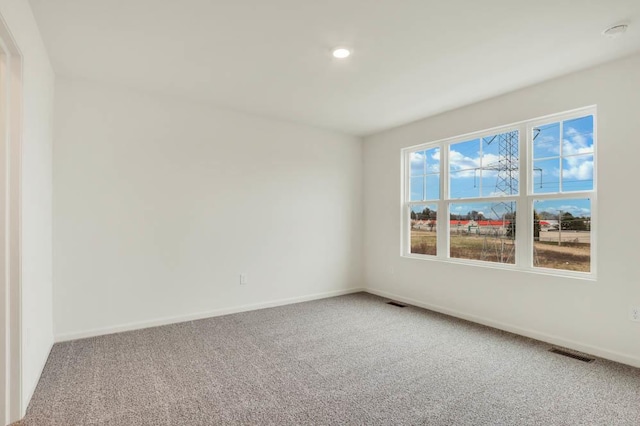 carpeted empty room with baseboards, visible vents, and recessed lighting