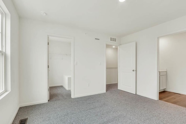 unfurnished bedroom featuring a spacious closet, visible vents, baseboards, and carpet floors