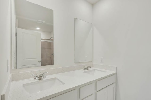 bathroom with a shower, double vanity, visible vents, and a sink