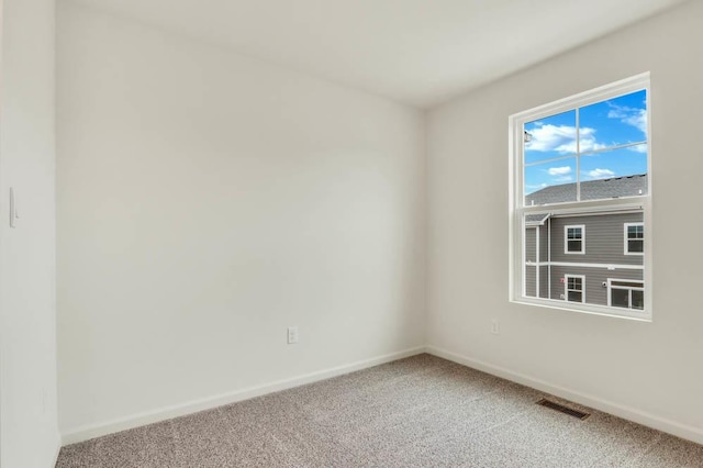 carpeted empty room featuring baseboards and visible vents