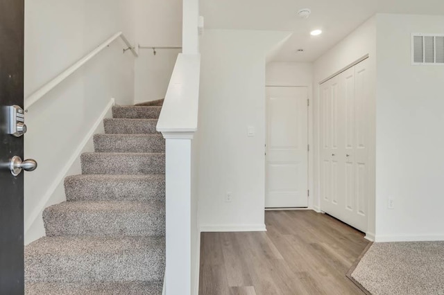 staircase with visible vents, baseboards, recessed lighting, and wood finished floors