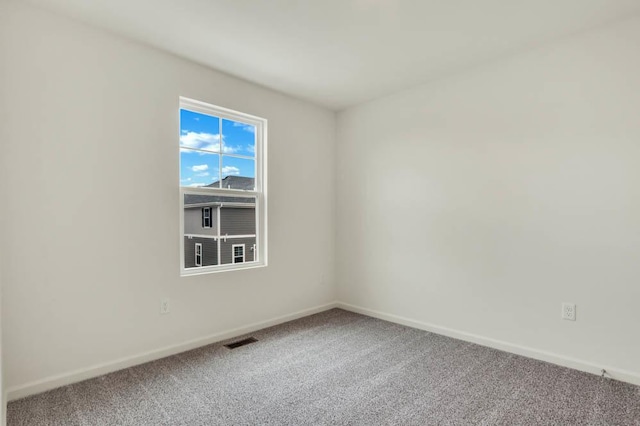 carpeted spare room with visible vents and baseboards