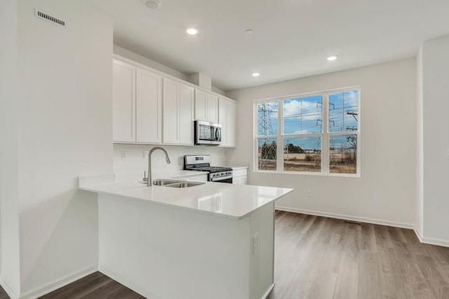 kitchen featuring light countertops, visible vents, appliances with stainless steel finishes, a sink, and wood finished floors