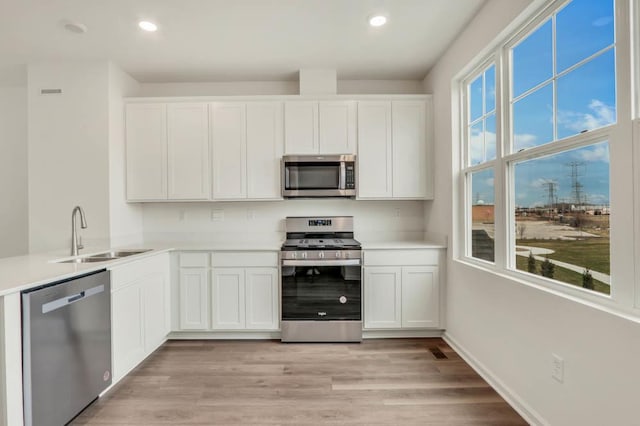 kitchen featuring light countertops, appliances with stainless steel finishes, a sink, and white cabinetry