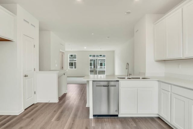 kitchen featuring a sink, stainless steel dishwasher, a peninsula, and white cabinets