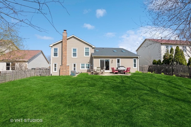 rear view of house with a fenced backyard, a chimney, and a lawn