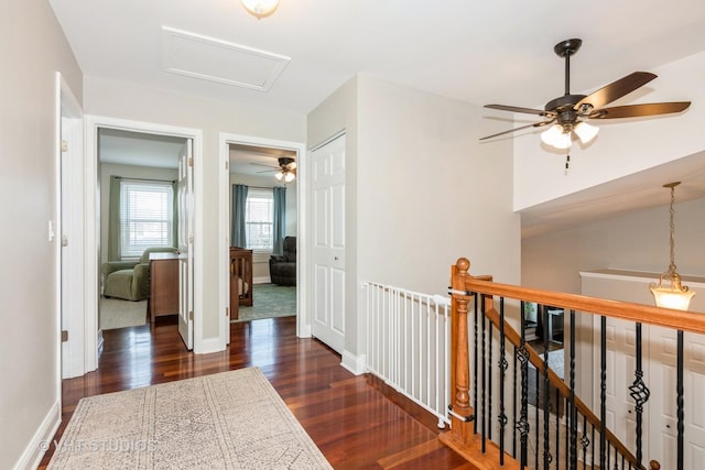 hall with baseboards, an upstairs landing, attic access, and dark wood-style floors