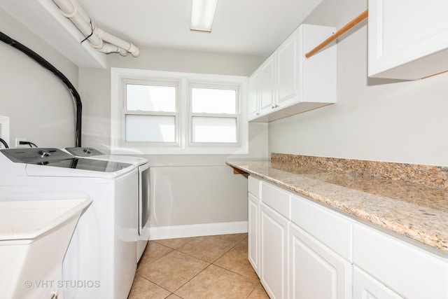laundry area featuring washing machine and clothes dryer, baseboards, cabinet space, and light tile patterned floors