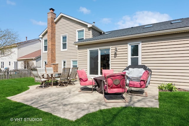 rear view of property featuring a patio, a chimney, fence, and a lawn