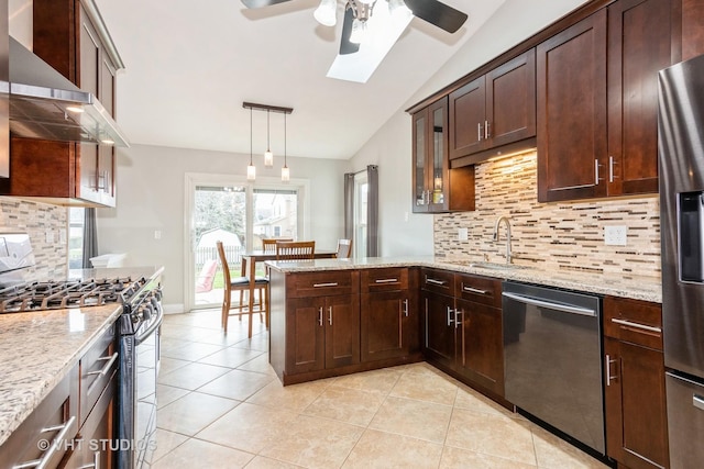 kitchen with appliances with stainless steel finishes, wall chimney range hood, lofted ceiling with skylight, a sink, and ceiling fan
