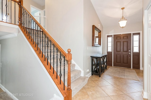 foyer with light tile patterned floors, baseboards, and stairs