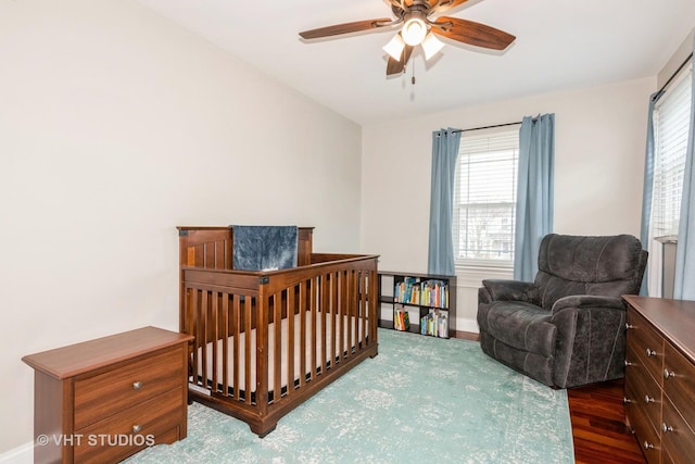 bedroom featuring multiple windows, baseboards, a ceiling fan, and wood finished floors