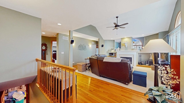 living room featuring ceiling fan, vaulted ceiling, wood finished floors, and visible vents