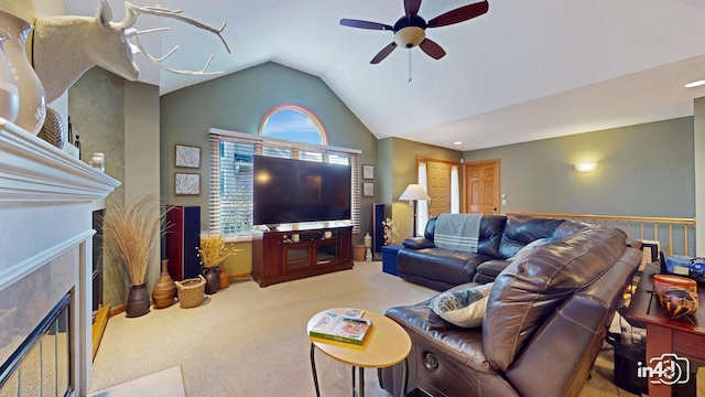 living area featuring a tiled fireplace, carpet, vaulted ceiling, and a ceiling fan